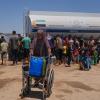 Eine palästinensische Frau schiebt einen Rollstuhl mit Plastikkanistern mit Wasser im Gazastreifen.