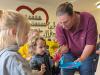 Die Kinder bekommen die Hände von einer Mitarbeiterin der Tagespflege angemalt.