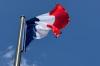 Die Frankreich-Flagge, auch Trikolore genannt, weht in der Pariser Innenstadt vor blauem Himmel.