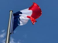 Die Frankreich-Flagge, auch Trikolore genannt, weht in der Pariser Innenstadt vor blauem Himmel.