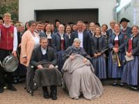 Anni Jais sitzt auf dem Stuhl vorne rechts, direkt daneben ihr Sohn Peter mit Ehefrau Uschi. Hinter Jais steht Bürgermeister Wilhelm Rehklau, ganz links Jürgen Hahn, Vorstandsmitglied der Musikkapelle Deiningen.