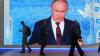Menschen gehen an einem Bildschirm mit einem Bild des russischen Präsidenten Wladimir Putin auf dem Internationalen Wirtschaftsforum vorbei.