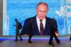 Menschen gehen an einem Bildschirm mit einem Bild des russischen Präsidenten Wladimir Putin auf dem Internationalen Wirtschaftsforum vorbei.